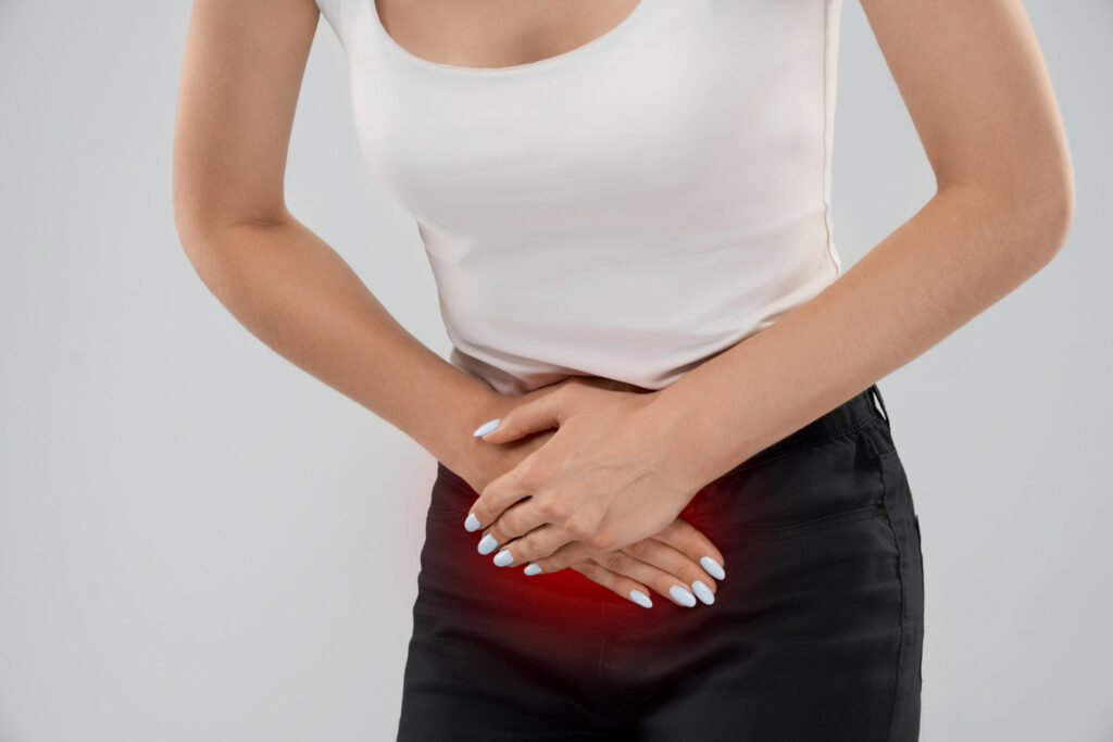Woman clutching her lower abdomen in pain, with a red glow indicating discomfort at the pelvic area
